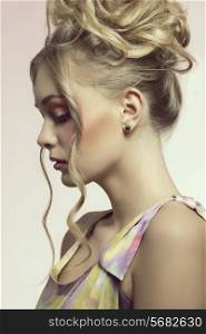 close-up shoot of pretty blonde woman with creative hairdo, colorful make-up and dress. Perfect skin. Beauty concept