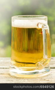 Close-up shot of a glass of beer on a wooden table.