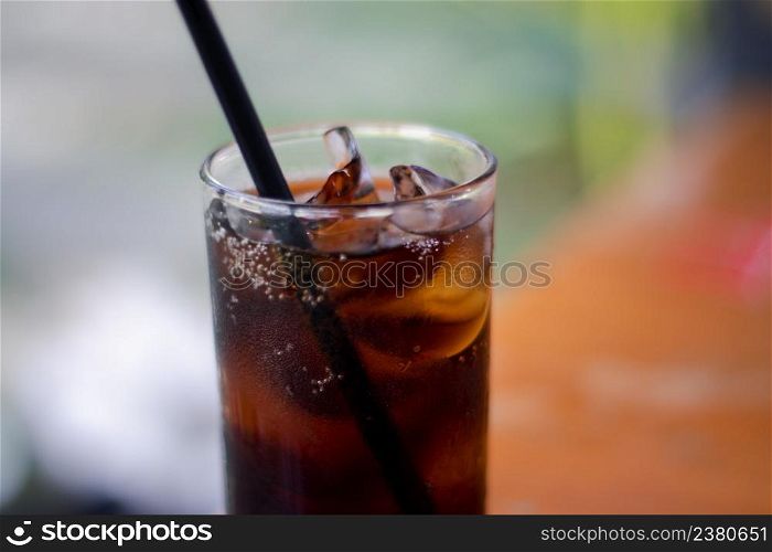 Close-up shot of a glass of cold cola. Soft drink, soft drink in a glass with ice on blurred background.
