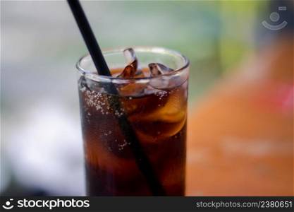 Close-up shot of a glass of cold cola. Soft drink, soft drink in a glass with ice on blurred background.
