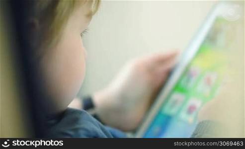 Close-up shot of a little boy playing with touchpad in the train