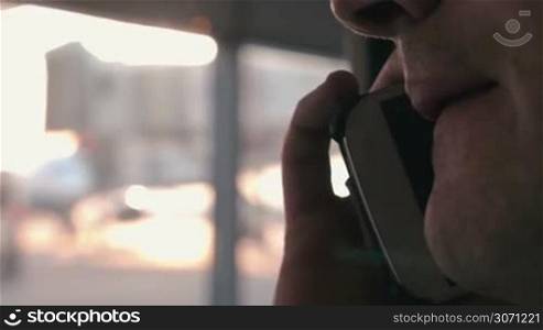 Close-up shot of a man having a phone talk at the airport. Blurred window in background