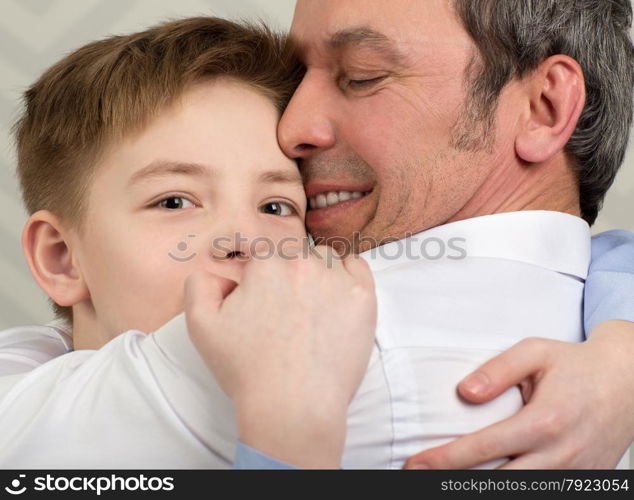 Close-up shot of a son giving father a hug. Boy devoted to his beloved dad