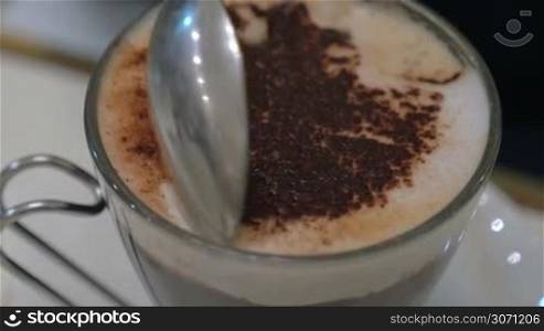 Close-up shot of a spoon stirring coffee foam and then taking it