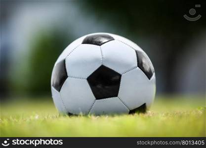 Close-up shot of a traditional football on green grass, symbol of the most popular team sports in the world