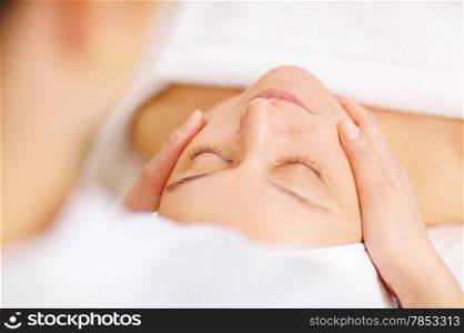 Close-up shot of a woman during the seance of facial massage in beauty spa