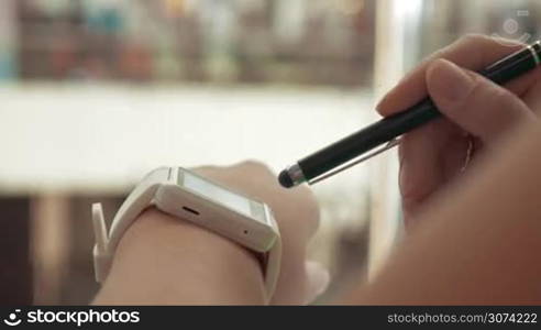 Close-up shot of a woman using smartwatch in the street. Convenient gadget to get in touch at any moment