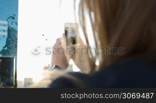 Close-up shot of a woman with phone taking pictures of the city