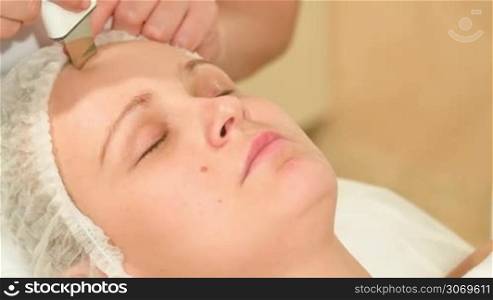 Close-up shot of a young woman being on seance of ultrasonic facial cleaning