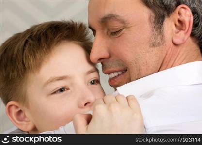 Close-up shot of an emotional embrace of son and father. Happy and close-knit family . Sincere love of parent and child