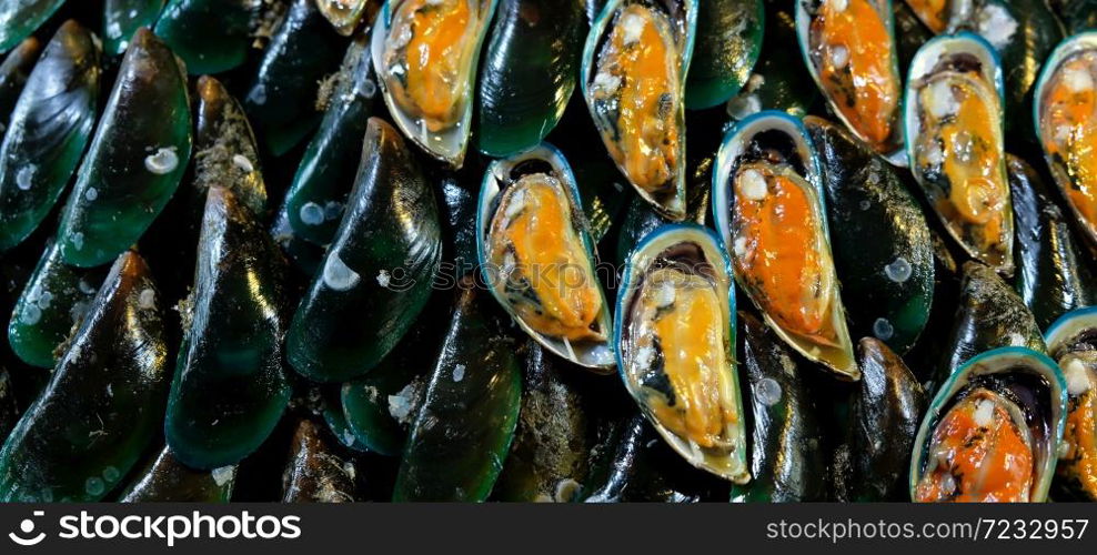 Close-up shot of Asian green mussels on ice, halved raw and fresh mussels are on sale at a local market. Top view. Flat lay.