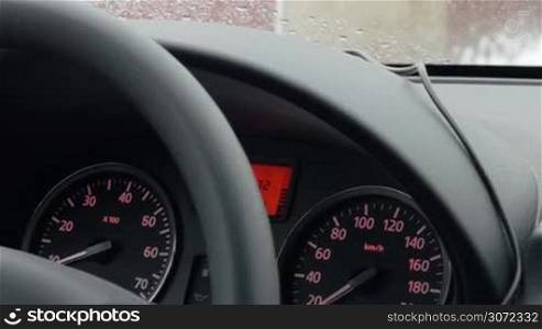 Close-up shot of car driving with dashboard view. Low speed can be seen on speedometer