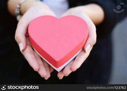 Close up shot of female hands holding heart shaped gift box. Valentines day, romance concept. . Female hands holding heart shaped gift box.