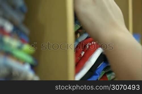 Close-up shot of female hands looking over the pile of colorful materials or clothing in the store
