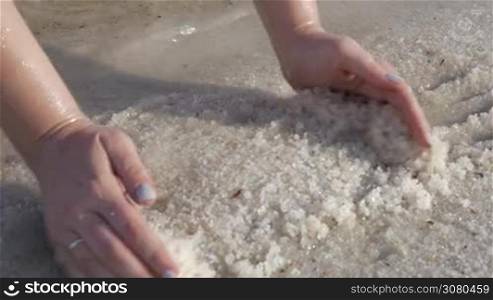 Close-up shot of female hands taking salt from the shore. Dead Sea recreation resort