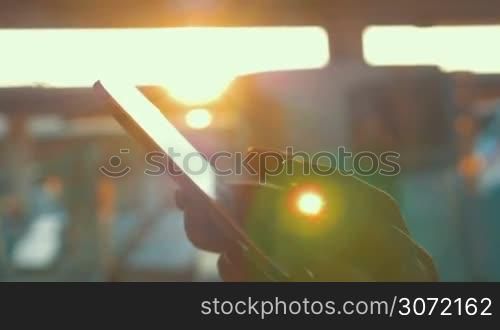 Close-up shot of female hands typing sms on smart phone on background of bright sun flare