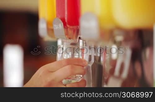 Close-up shot of female hands using juice pouring machine