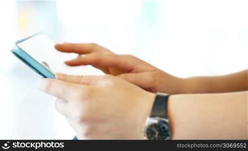 Close-up shot of female hands working with tablet PC on light background