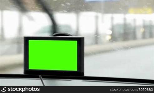 Close-up shot of GPS device with chroma key in moving car, windscreen wipers working