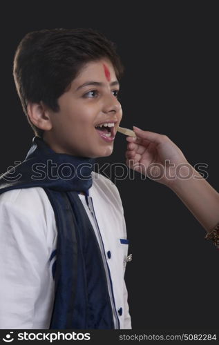 Close up shot of hand feeding sweets to her brother at Bhaidooj