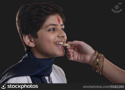 Close up shot of hand feeding sweets to her brother at Bhaidooj