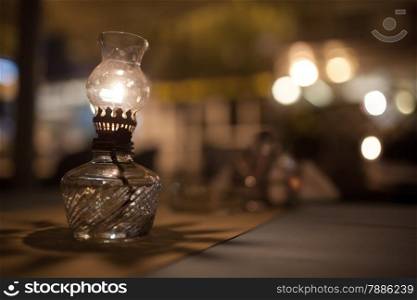 Close-up shot of lit vintage oil lamp standing on the table in a cafe. Warm and cozy atmosphere