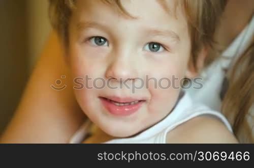 Close-up shot of lovely little boy sitting on mothers lap