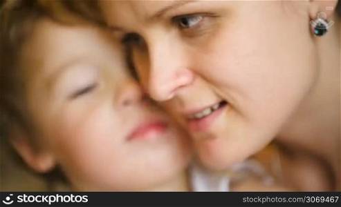 Close-up shot of loving family of little son and his young mother kissing each other