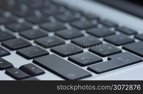 Close up shot of male hand typing on a modern laptop keyboard and then pressing enter