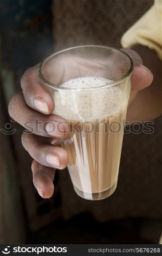 Close-up shot of male&rsquo;s hand holding glass of Indian milk tea