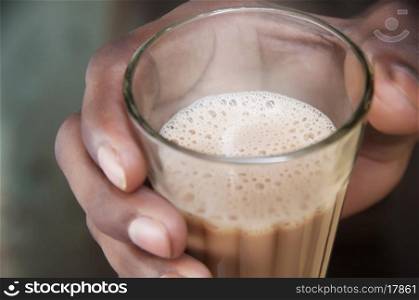 Close-up shot of man's hand holding glass of chai