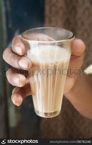 Close-up shot of man&rsquo;s hand holding glass of chai