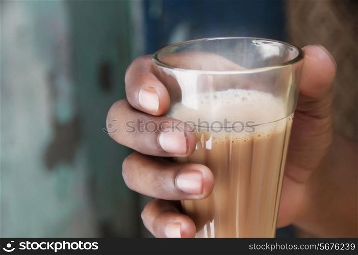 Close-up shot of man&rsquo;s hand holding glass of Indian milk tea