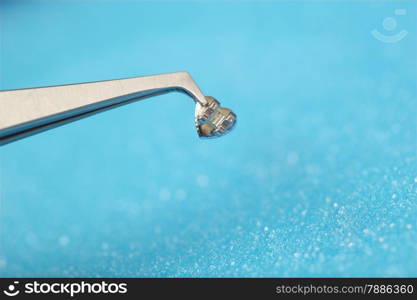 Close-up shot of pincers holding single bracket. Stomatology and teeth care