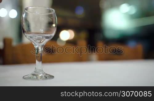 Close-up shot of pouring white wine into glass on the table in restaurant. Alcoholic drinks