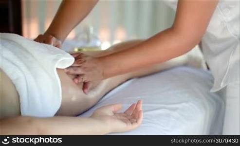 Close-up shot of professional massage therapist making a hip massage in beauty spa. Body and health care