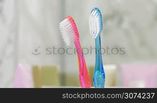 Close-up shot of putting small childs toothbrush into the cup with two of adults. Family having a baby