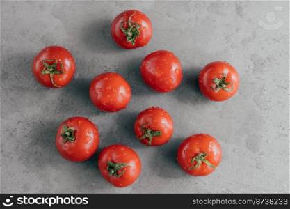 Close up shot of red heirloom tomatoes studded with drops of water against grey background. Fresh vegetables. Horizontal shot.