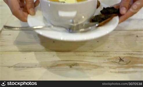 Close-up shot of serving hot soup with cream and bruschettas in cafe or restaurant. Woman stirring soup with spoon