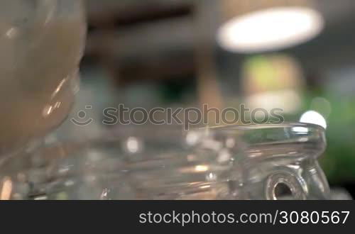 Close-up shot of serving masala tea in the restaurant. Pouring Indian hot drink into a glass tea bowl