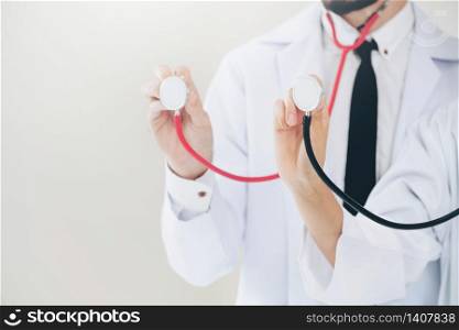 Close up shot of two doctors pointing stethoscope at copy space. Selective focus at front doctors hand.. Close up shot - doctors point stethoscope at space