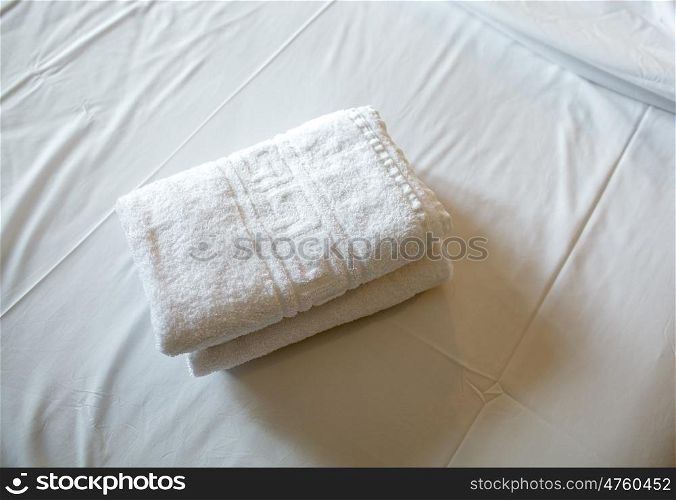 Close-up shot of two fresh clean towels on the bed with white sheet