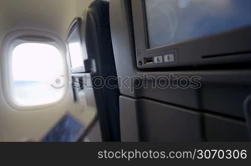 Close-up shot of woman connecting smart phone with seat monitor in plane using USB cable
