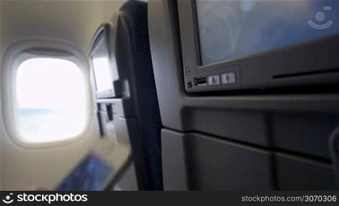 Close-up shot of woman connecting smart phone with seat monitor in plane using USB cable