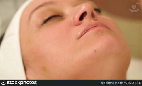 Close-up shot of woman on seance of facial massage with accent on chin