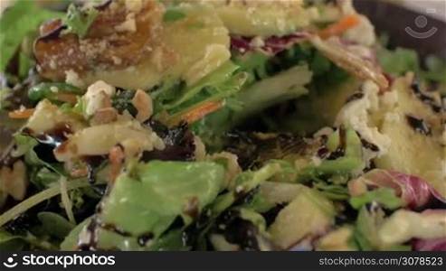 Close-up shot of woman pouring green mixed salad with lemon juice and eating it. Healthy light food