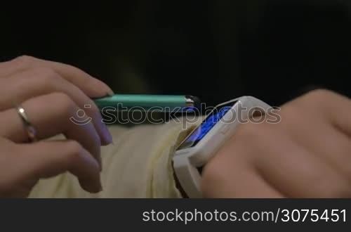 Close-up shot of woman with smart watch typing phone number with pen on touchscreen