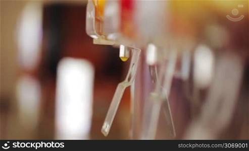 Close-up shot of womans hands pouring orange juice into the glass using the machine in a cafe