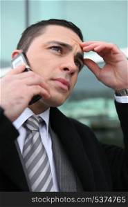 close-up shot of young businessman on the phone looking preoccupied