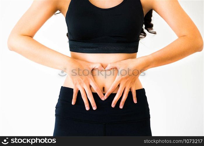 Close up shot of young woman in sportswear making heart shape gesture at her abdomen. Dieting weight loss and healthy nutrition concept.